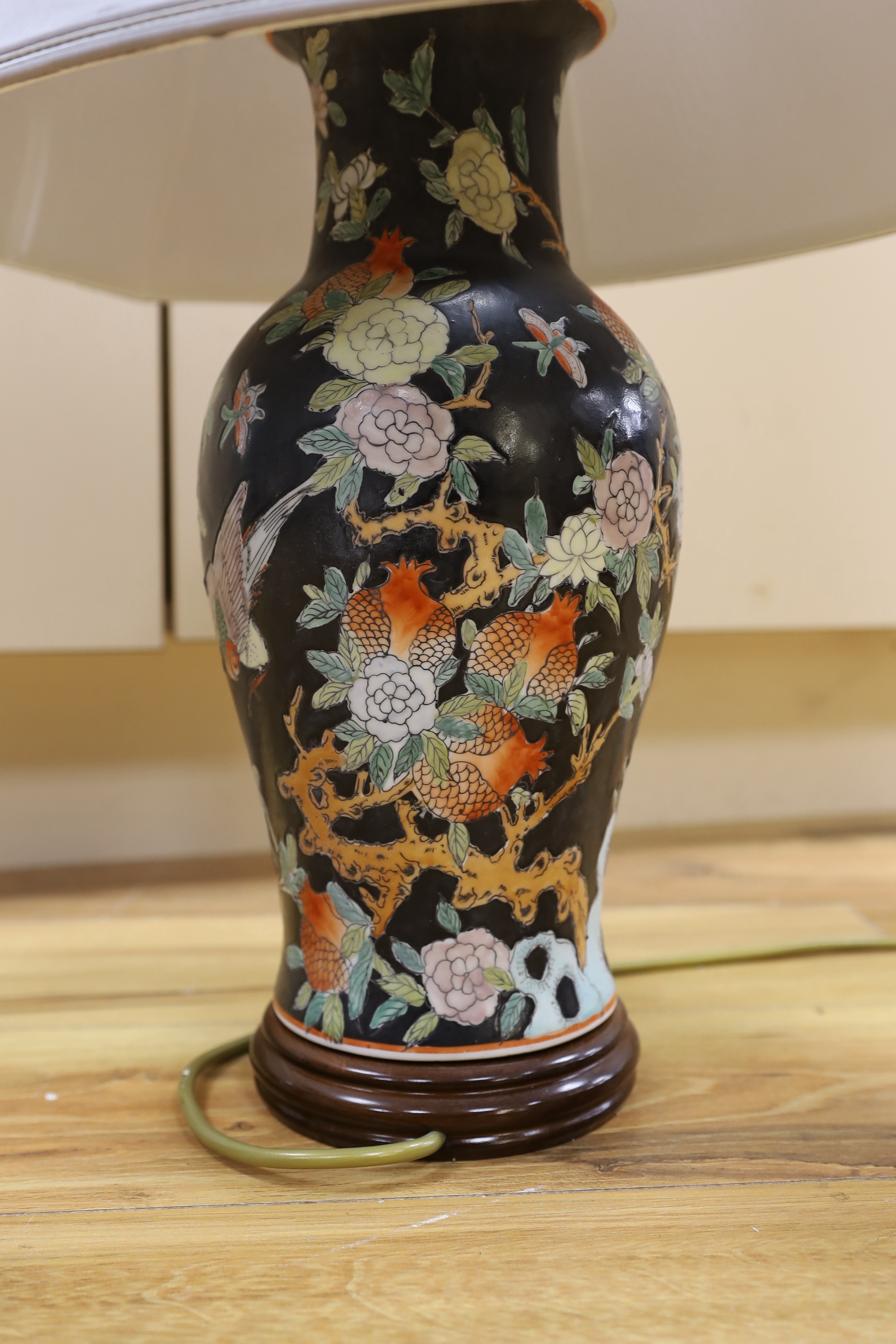 A Chinese famille noire table lamp and a pink ground Chinese vase, both on wooden stands, tallest vase 39cm